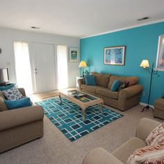 a living room with couches, chairs and a coffee table in front of a blue wall