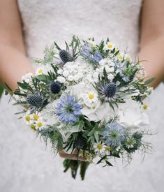 a bride holding a bouquet of white and blue flowers