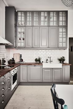 a kitchen with gray cabinets and white tile backsplash