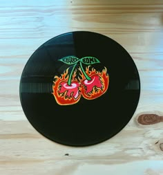 a black record with two cherries on it sitting on top of a wooden table