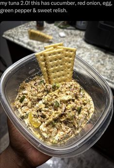 a person holding up a bowl of food with crackers in it and the caption reads, my tuna 21 this is cucumber, red onion, egg, green pepper & sweet relish