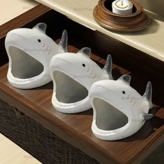 three ceramic toothbrush holders in the shape of rhinoceros on a wooden tray