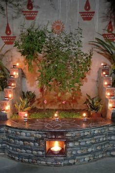 an outdoor fire pit with candles lit in the center and plants growing out of it