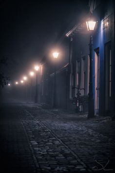 an empty cobblestone street at night in the fog