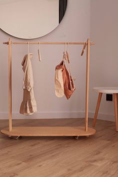 two towels hanging on a clothes rack in front of a mirror and table with stools