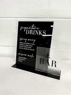 a black and white photo of a bar sign with the name of some drinks on it