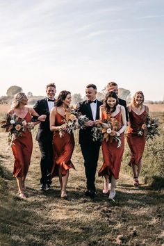 a group of people that are standing in the grass with one person wearing a suit and tie