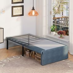 a bed frame sitting on top of a wooden floor next to a window with white curtains