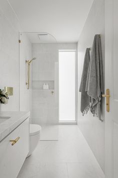 a white bathroom with gold handles and towels