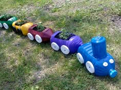 a train made out of plastic sitting on top of the grass next to a potted plant