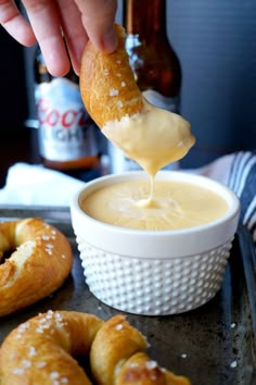 a person dipping something into a bowl with pretzels