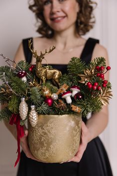 a woman holding a potted plant with christmas decorations