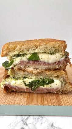 two sandwiches stacked on top of each other with cheese and spinach in between them