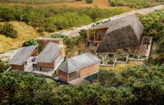 an aerial view of two wooden buildings in the middle of a field with trees and grass