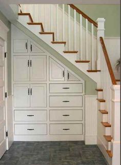 an empty room with drawers under the stairs