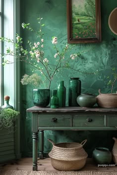 green vases are sitting on a table in front of a painting and other items