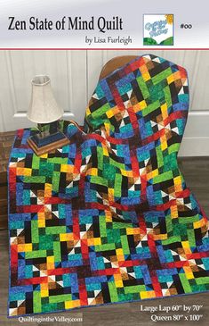 a colorful quilt sitting on top of a wooden floor next to a lamp and table