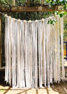 an outdoor wedding ceremony with white sheer curtains and pom poms hanging from the ceiling