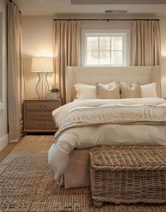 a large bed sitting under a window next to a dresser and lamp in a bedroom