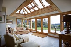 a living room filled with furniture and windows covered in wooden frame doors that look out onto a lush green field