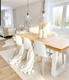 a dining room table with white chairs in front of a large window and rug on the floor