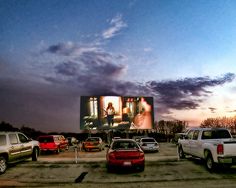 several cars parked in a lot with a large screen