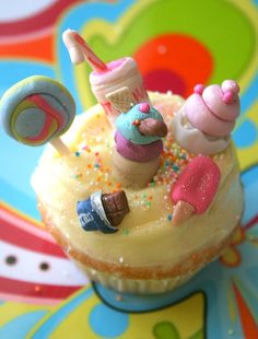 a cupcake decorated with small toys on top of it's icing and sprinkles