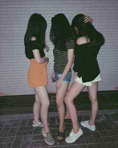 three young women standing next to each other in front of a garage door with their arms around one another