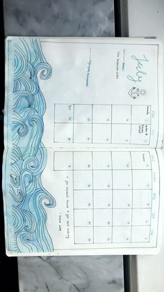 an open planner with blue waves on it and the date circled in white paper, sitting on a marble counter top