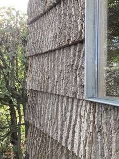 a window on the side of a house that is covered in wood shingles and moss