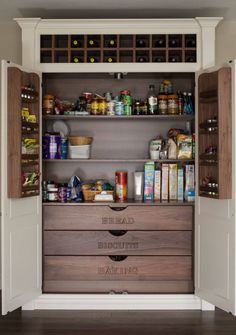 an open pantry filled with lots of food and condiments on top of wooden drawers