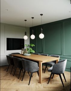 a dining room with dark green walls and wooden flooring, black chairs and a table surrounded by hanging lights