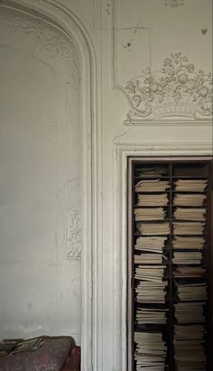 an open bookcase filled with lots of books next to a wall covered in white paint