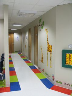 an office hallway decorated with giraffes on the wall and colorful flooring