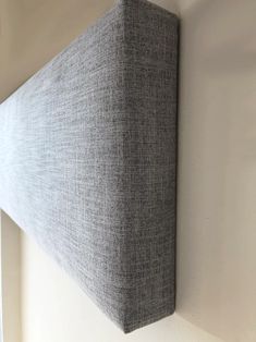 the corner of a wall hanging on a white wall with a gray fabric covering it