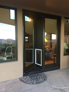 the front door to a home with glass doors and an iron grill on the patio