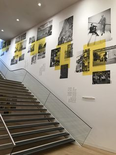 the stairs are lined with yellow and black photos on the wall behind them is a set of metal handrails