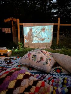 an outdoor movie screen is set up in the grass with pillows and blankets on it