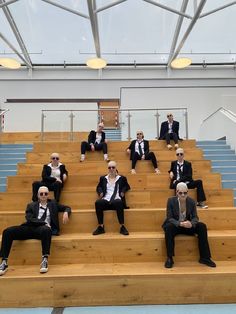 several men in suits sitting on some steps with their legs crossed and one man wearing sunglasses