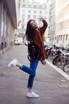 a woman is walking down the street with her hand up in the air and smiling