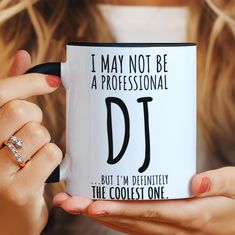 a woman holding a coffee mug that says i may not be a professional dj but i'm definitely the coolest one