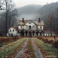 an old house in the middle of a field with leaves on the ground and mountains in the background