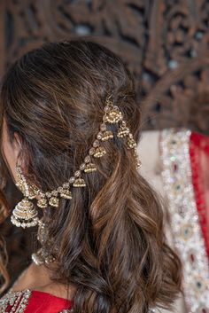 a woman with long brown hair wearing a red dress and gold jewelry on her head