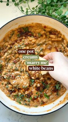 a person is holding a spoon in a bowl with beans and spinach on it