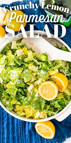 a white bowl filled with salad on top of a blue towel next to lemons