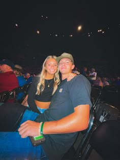 a man and woman sitting next to each other in front of an audience at a sporting event