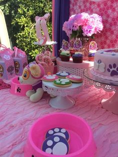 a pink table topped with lots of cakes and cupcakes