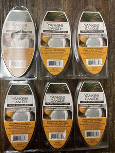 six yankee candles in plastic packaging on a wooden table