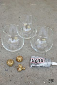 four empty wine glasses sitting on top of a cement floor next to small gold objects