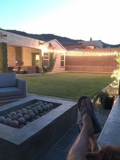 a person sitting in front of a fire pit with their feet up